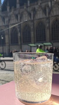 Sparkling soft drink with ice served on caf&eacute; terrace overlooking street traffic and pedestrians near &Eacute;glise Notre-Dame du Sablon, Brussels &ndash; Petit Sablon city view