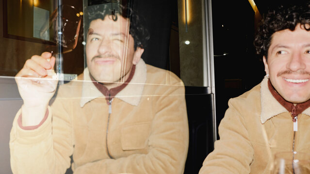 Double exposure portrait of man holding wine glass at night