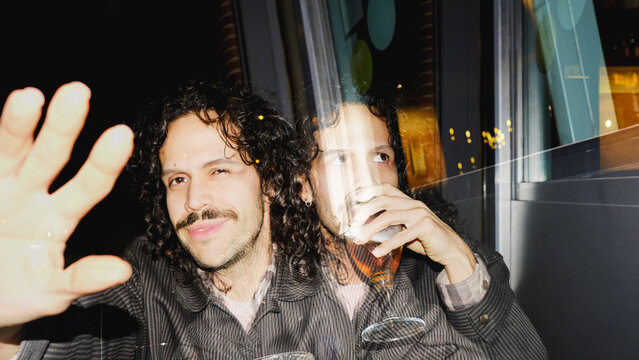 Double exposure portrait of man with raised hand at night