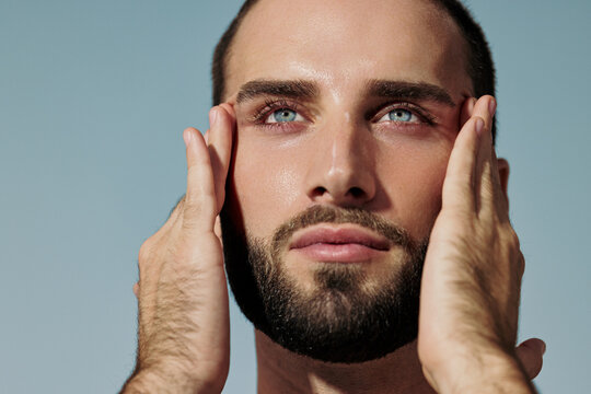 Man Touching Face With Hands in Natural Light at Indoor Location