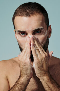 Man Washing His Face in a Simple Bathroom Setting During the Day