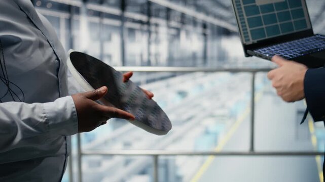 Researchers evaluating advanced microchip silicon wafer prototype, analyzing electronic components. Workers holding semiconductor substrate in smart factory, developing new hardware, camera A close up