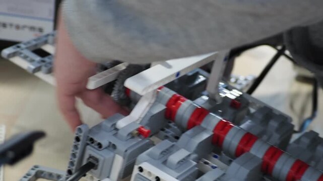 young boy constructor scientist assemble the wheeled machine robot in the lab. boy teenager collects according to instructions robot constructor. connects wires, programs. develops intelligence