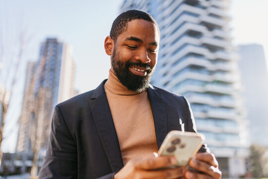 Happy businessman send texts via his phone