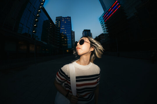 Woman exploring urban cityscape at dusk with fisheye perspective