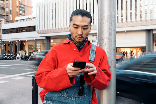 Young asian man using phone on urban street