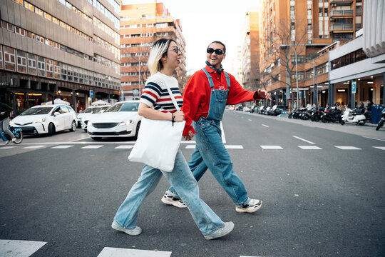 Young couple crossing city street holding hands
