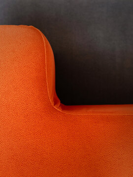 Close-up of bright orange textured armchair against dark background