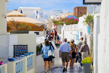 A crowded narrow pedestrian walkway past whitewashed buildings with shops and cafes in the...