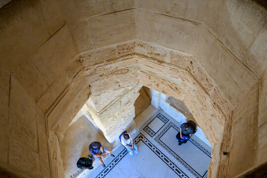 View of tourists sitting in a mosaic floored room on the level below from an oil hole or machicolation hole designed to dump hot oil on invaders inside the Qaitbay Citadel in Alexandria Egypt.