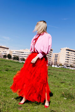 Woman wearing red tulle skirt standing in field