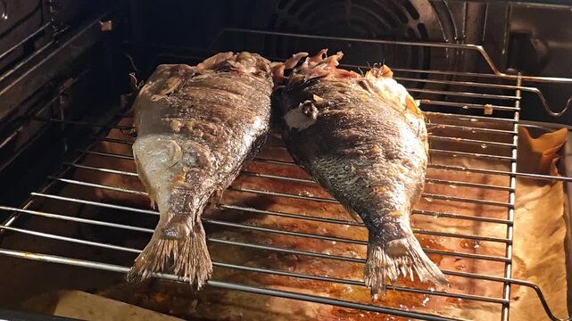 Two whole grilled sea bream fish laying on an oven wire rack, perfectly roasted until golden brown, prepared for a healthy Mediterranean seafood dinner.