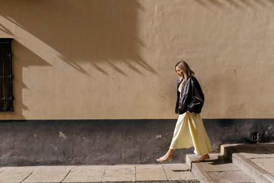 Woman walking urban street with sunlight