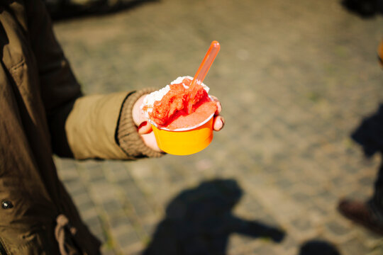 Hand holding a cup of gelato, eating ice ream in Italy