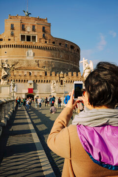 Back shot of tourist taking a photo of Castel Sant'Angelo in Rome