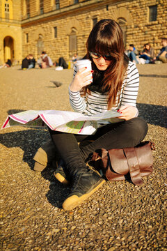 Young woman looking at a tourist map in Florence and drinking coffee
