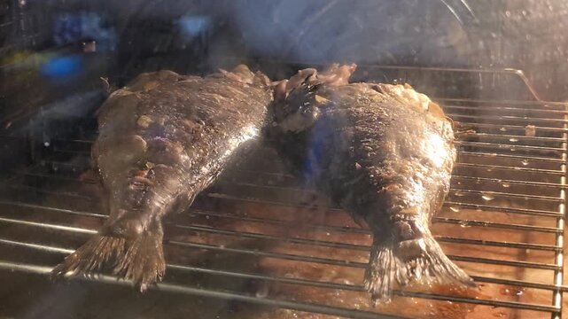 Two whole grilled sea bream fish laying on an oven wire rack, perfectly roasted until golden brown, prepared for a healthy Mediterranean seafood dinner.