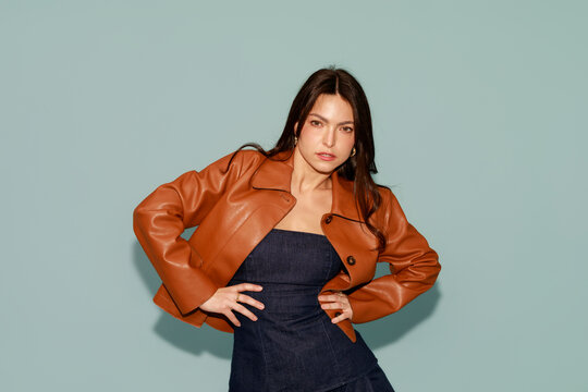 Woman Poses in a Brown Jacket Against a Blue Background