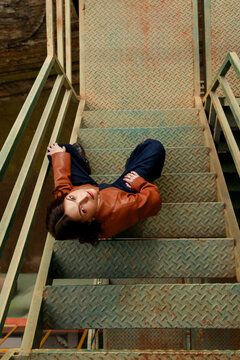 Young Person Sits on Metal Stairs in Industrial Setting