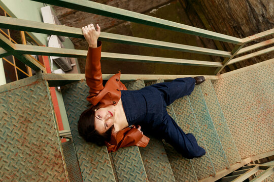 Woman Poses on Metal Stairs in Urban Setting 