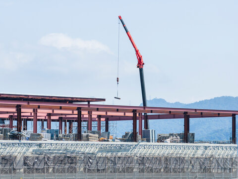 Red Crane Lifting Steel Beam at Construction Site