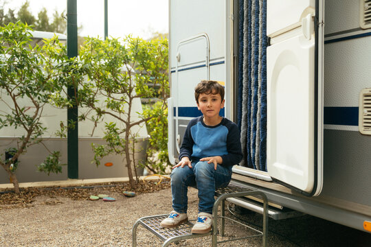 Young boy sitting entrance step of camper van