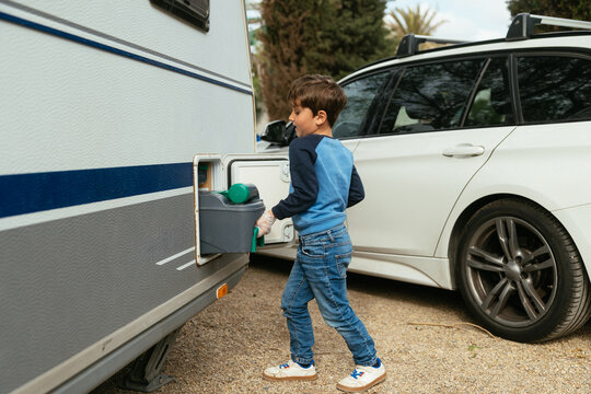 Boy removing waste tank from caravan toilet