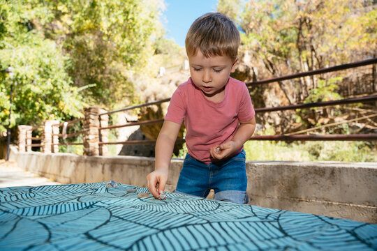 Young boy playing with stones on outdoor table