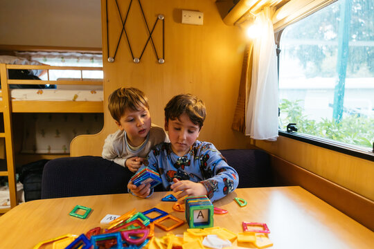 Young brothers playing with magnetic building blocks in caravan