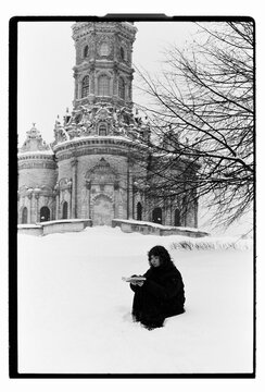 Film B&W Portrait of a Woman Sitting in Snow by Baroque Church
