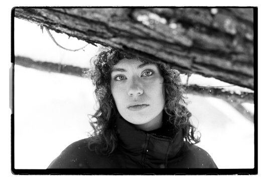 Film B&W Close-Up Portrait of a Woman Under Tree Branch in Snow
