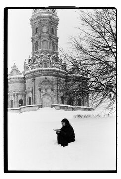 Film B&W Portrait of a Woman Sitting in Snow by Baroque Church