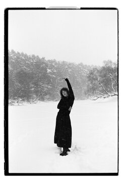 Film B&W Portrait of a Woman Raising Arm in Snowy Field