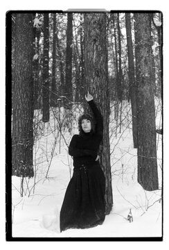 Film B&W Portrait of a Woman by Pine Tree in Snowy Forest