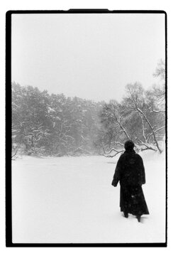 Film B&W Photo of a Woman Walking in Blizzard Across Snowy Field