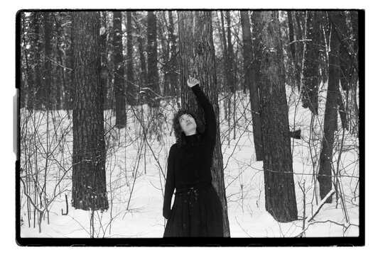 Film B&W Portrait of a Woman by Pine Tree in Snowy Forest