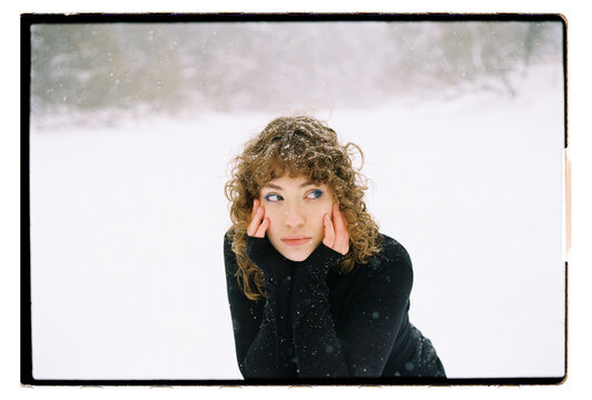Film Portrait of a Woman Holding Face in Hands During Snowfall