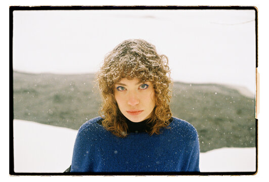 Film Portrait of a Woman with Curly Hair in Snowfall Outdoors