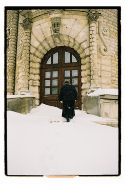 Film Photo of a Woman Standing at Stone Arch Door in Snowstorm