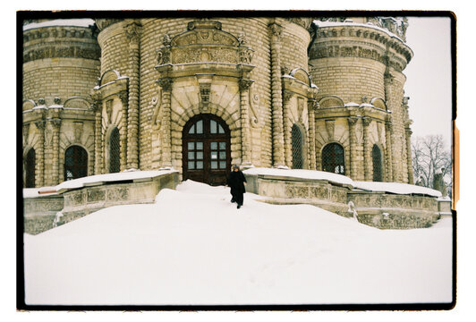 Film Photo of a Woman at Ornate Stone Church Entrance in Snow