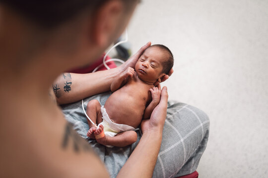 Father holding newborn baby skin-to-skin at hospital