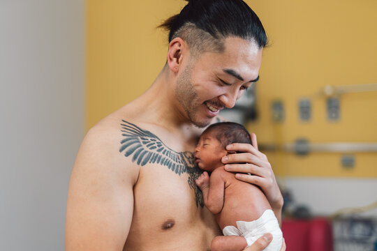 Father holding newborn baby skin-to-skin in hospital