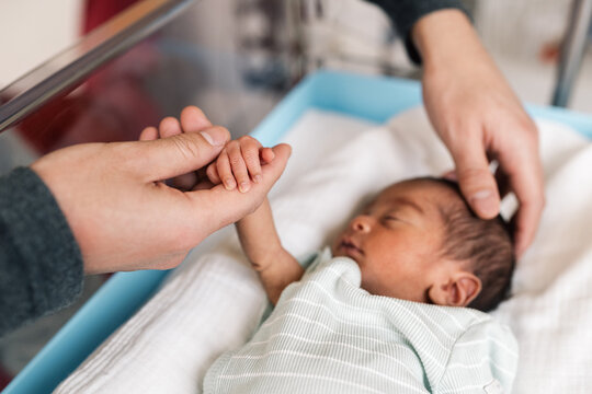 Father holding newborn baby hand in hospital
