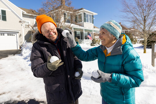 Senior couple laugh snowball fight winter 