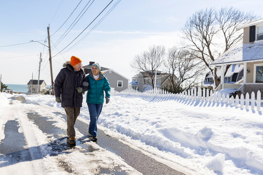 Senior couple winter neighborhood walk hold hands 