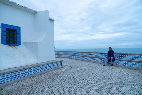 A blue woman sitting by an old church bench 
