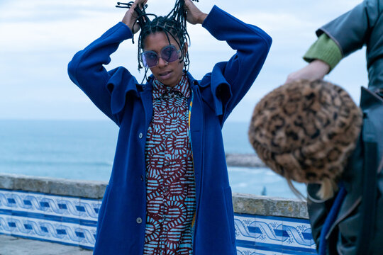 A blue woman posing for a photographer by sea in town