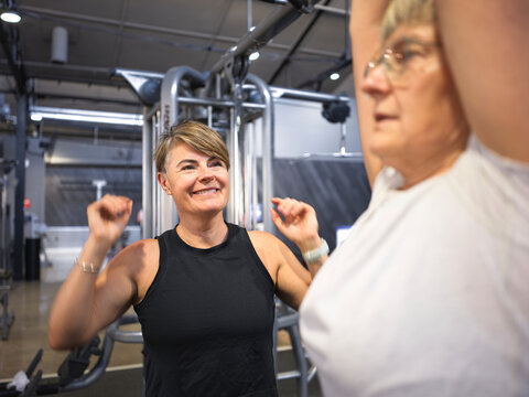 Personal Trainer encouraging client during workout session at gym