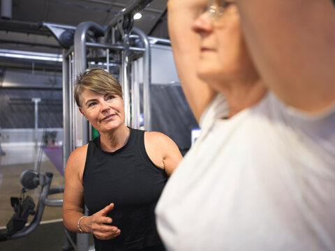 Personal Fitness Trainer instructing client at Gym 
