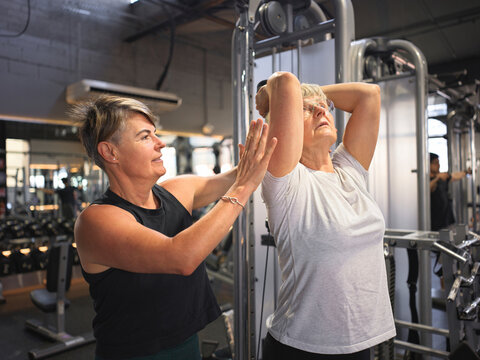 Personal trainer intructing client on exercise machines at gym